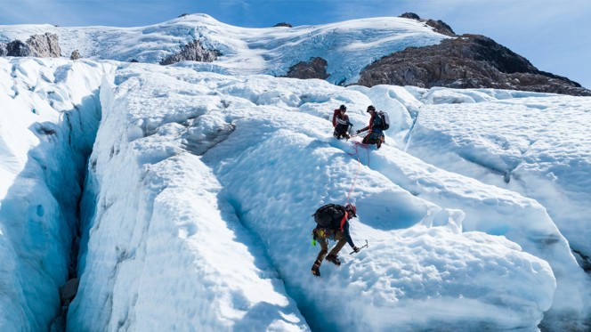 A group of climbers using ice picks to cross a glacier in Chile.
